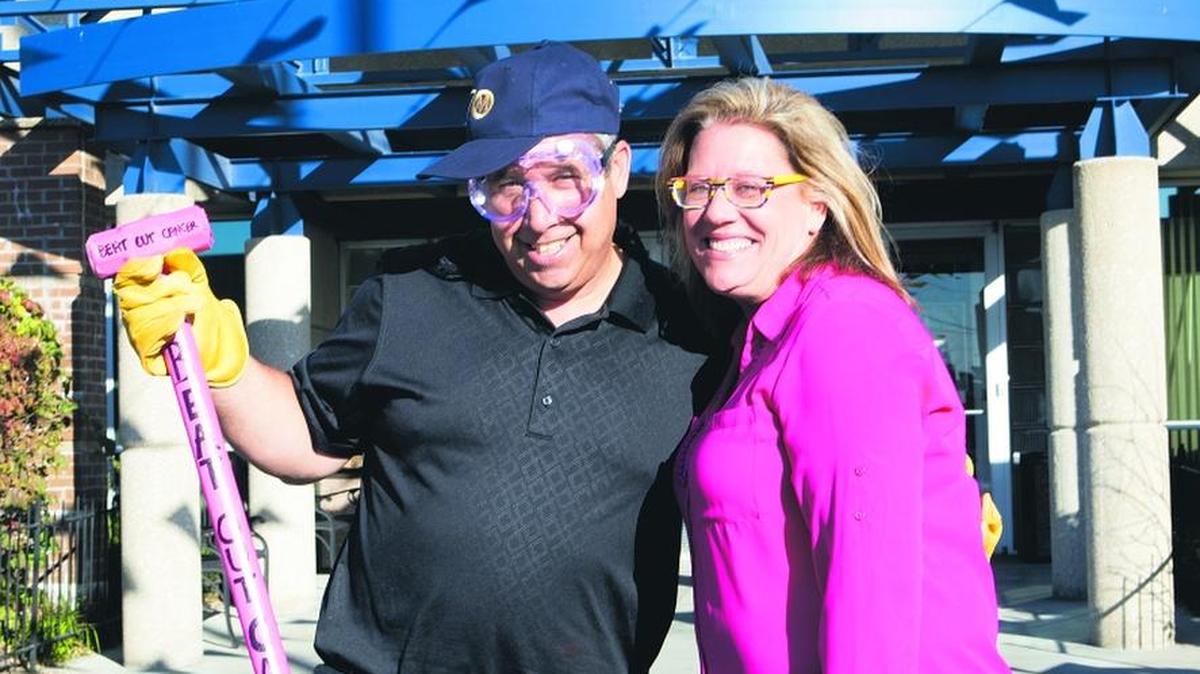 Michael Jayne from Truck City, Inc., in Des Moines, who was ready to take a swing at the “Beat Out Cancer” Lincoln Town Car, stands next to Peggy Sprenger, the general manager of Manheim Kansas City, at Manheim’s celebration of 70 years in business. The breast cancer fundraiser for Susan G. Komen of Greater Kansas City was part of the celebration.