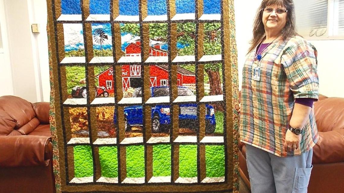 Connie Henry stands next to the quilt she made. She is the head nurse at the Ford Assembly Plant where the F-150 truck is built.