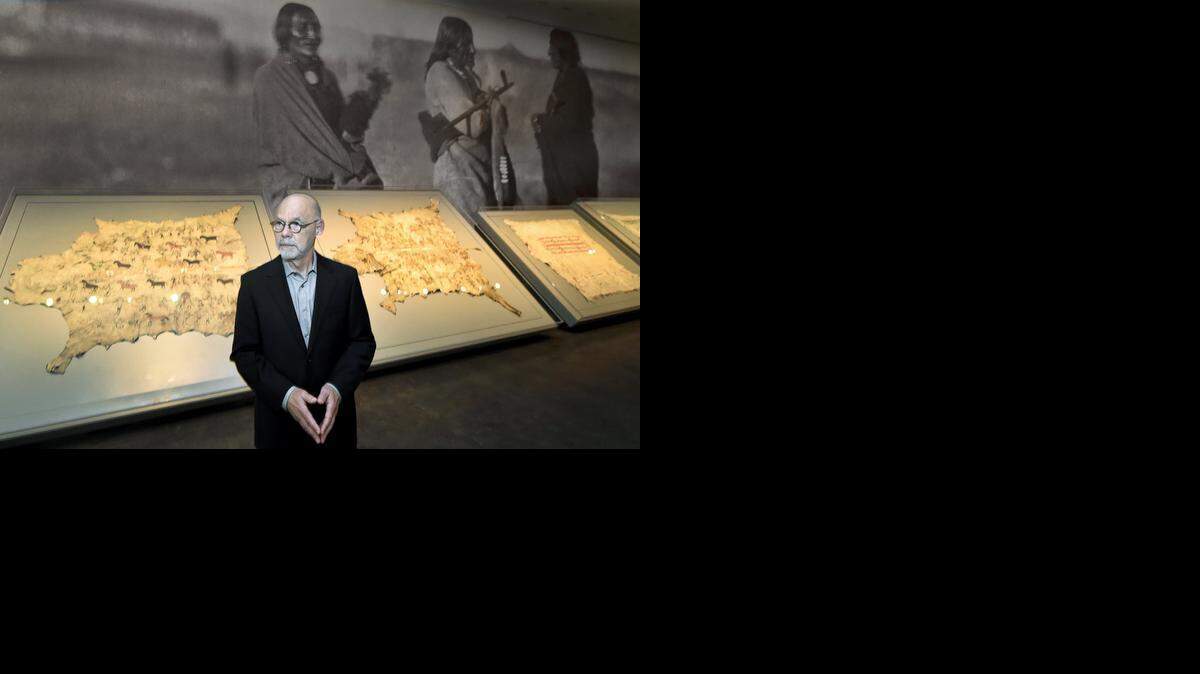 
Curator Gaylord Torrence stands before the centerpiece of the Plains Indian art exhibit, a grouping of five rare buffalo robes displayed in lighted cases against a wall-scaled enlargement of an 1868 photograph by Alexander Gardner from the museum’s collection.
