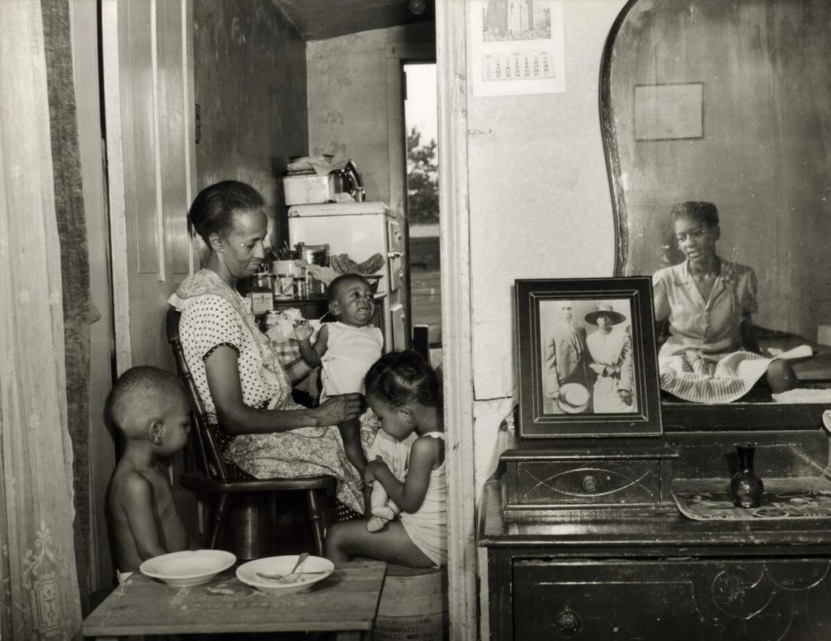 A photo from Gordon Parks’ famous series of Ella Watson, a government cleaning woman. She is seen here with her three grandchildren and her adopted daughter in July 1942.