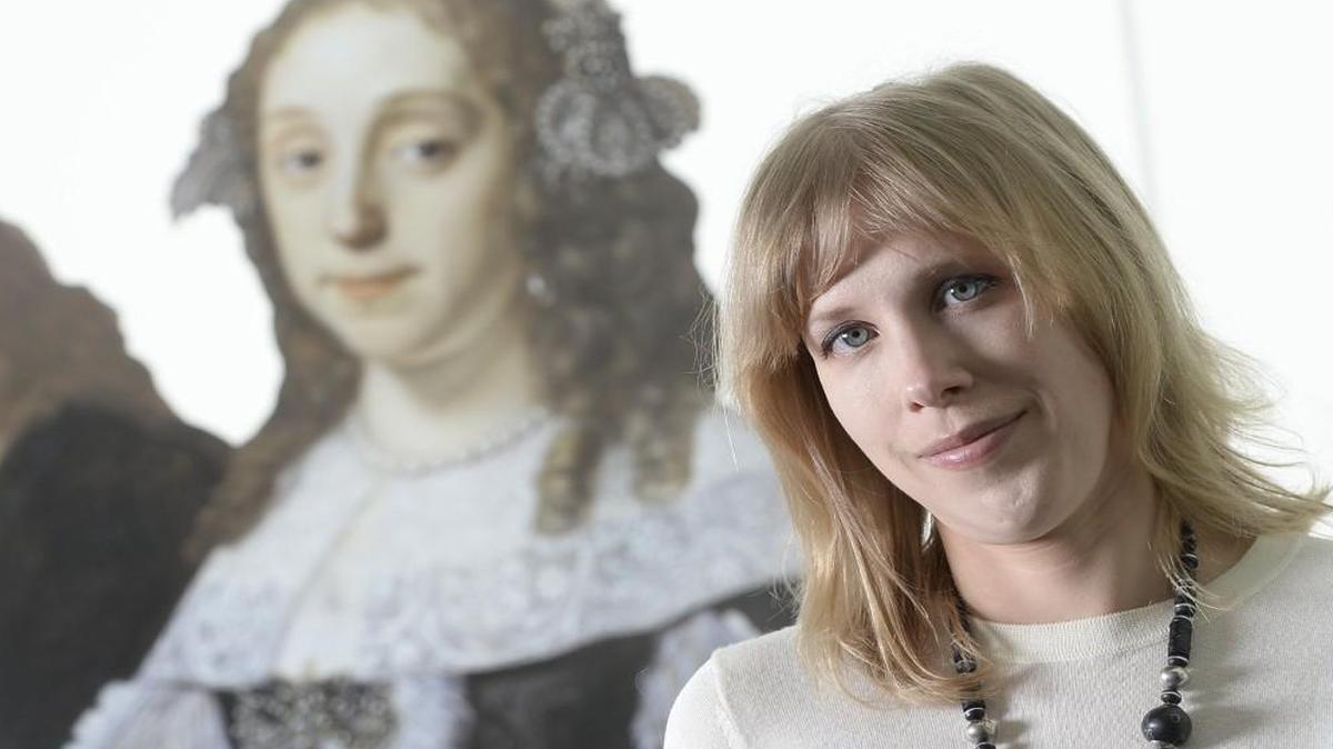 Rima Girnius, associate curator of European painting and sculpture at the Nelson-Atkins Museum of Art, helped prepare “Reflecting Class in the Age of Rembrandt and Vermeer,” which runs through May 29. Behind Girnius is a reproduction of one of the exhibit’s paintings that depicts Lucia Wijbrants, wife of Jan Hinlopen.