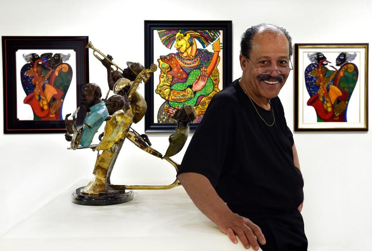 Ed Dwight in 2016, with his bronze sculpture on display at the American Jazz Museum. Behind Dwight are the paintings of Charles Biggs.