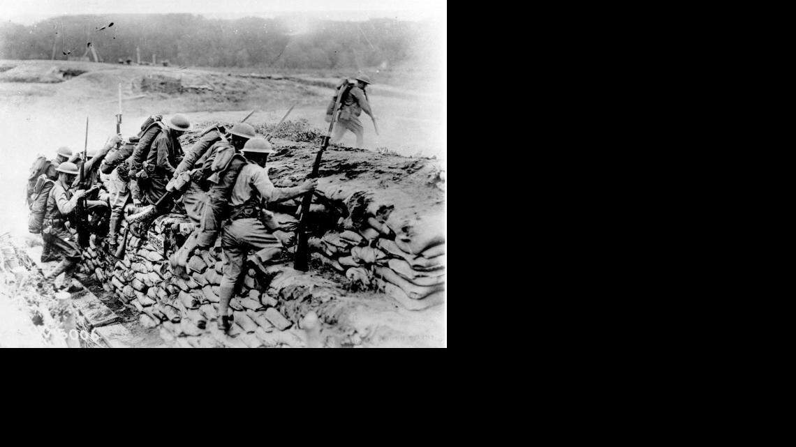 
In this 1918 file photo, American troops carrying guns with fixed bayonets climb over a sandbag revetment in France during World War I. 
