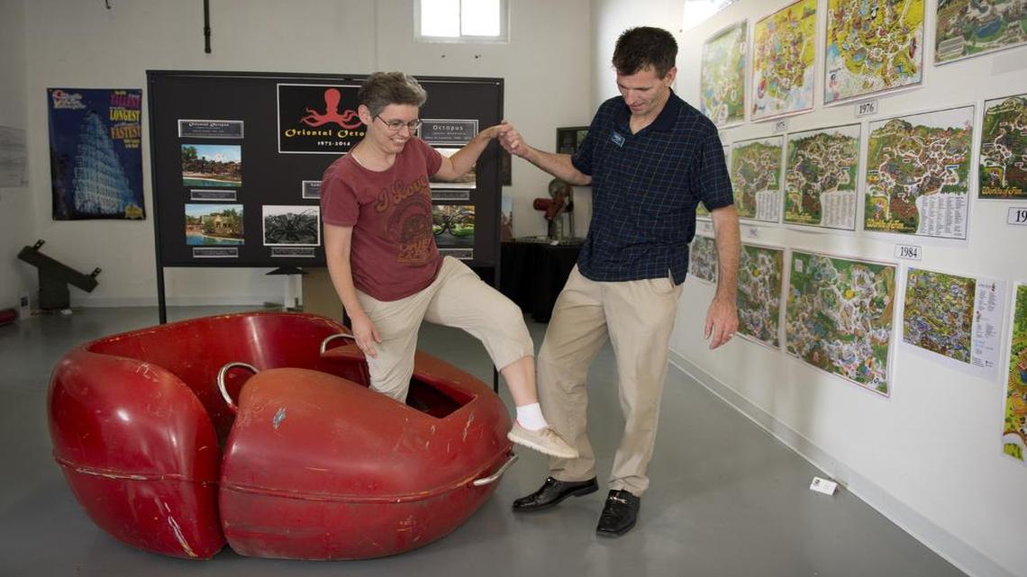 
Randal Strong-Wallace, director of the Roller Coaster Model Museum, helps collector Jennifer Lovesee-Mast from an old Octopus car going on display. On the wall are Worlds of Fun park maps from over the years.
