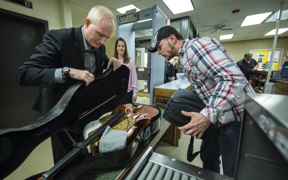 
As the musicians went through security at the prison, Alex East opened his cello case to let correctional officer Nathan Johnson (right) inspect it. The instrument was too big to fit through the X-ray machine.

