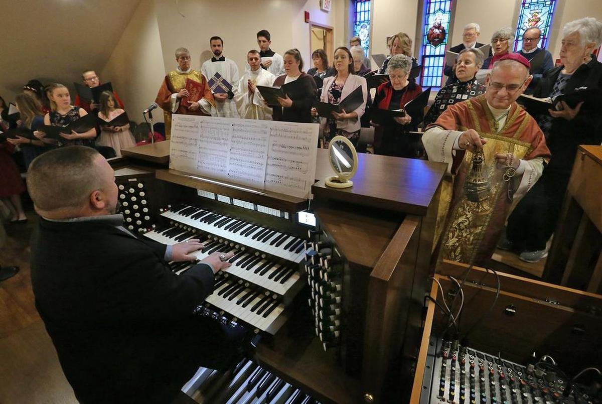 Organist Jeremy Boyer waits to play the new organ at St. Francis of Assisi Church in Oakville, Mo., while Bishop Mark Rivituso (right) blesses it.