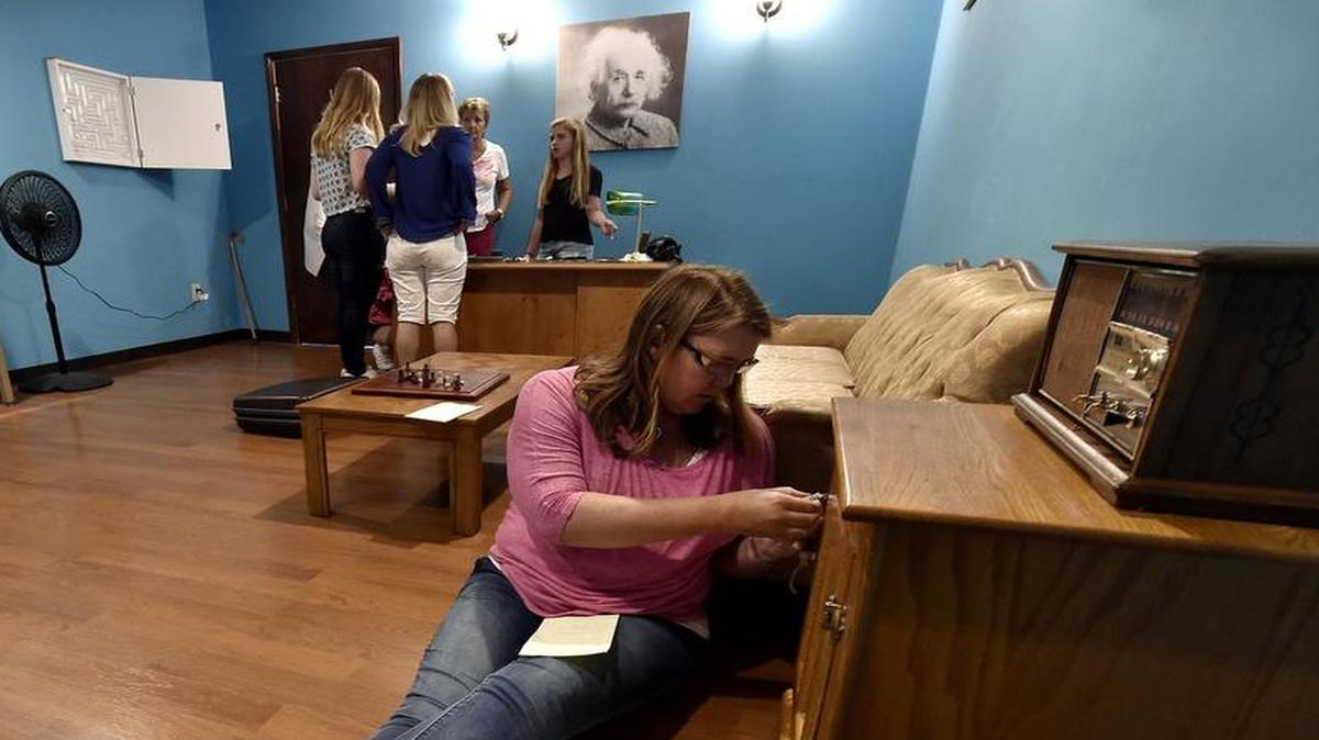 
While her teammates put their heads together, Shannon McKown (front) tries different combinations to open a cabinet that holds vital clues that will prove essential in the group’s escape from the Theory of Everything room. It’s one of three themed rooms in the Escape Room attraction at 511 W. Fourth St. in Kansas City.
