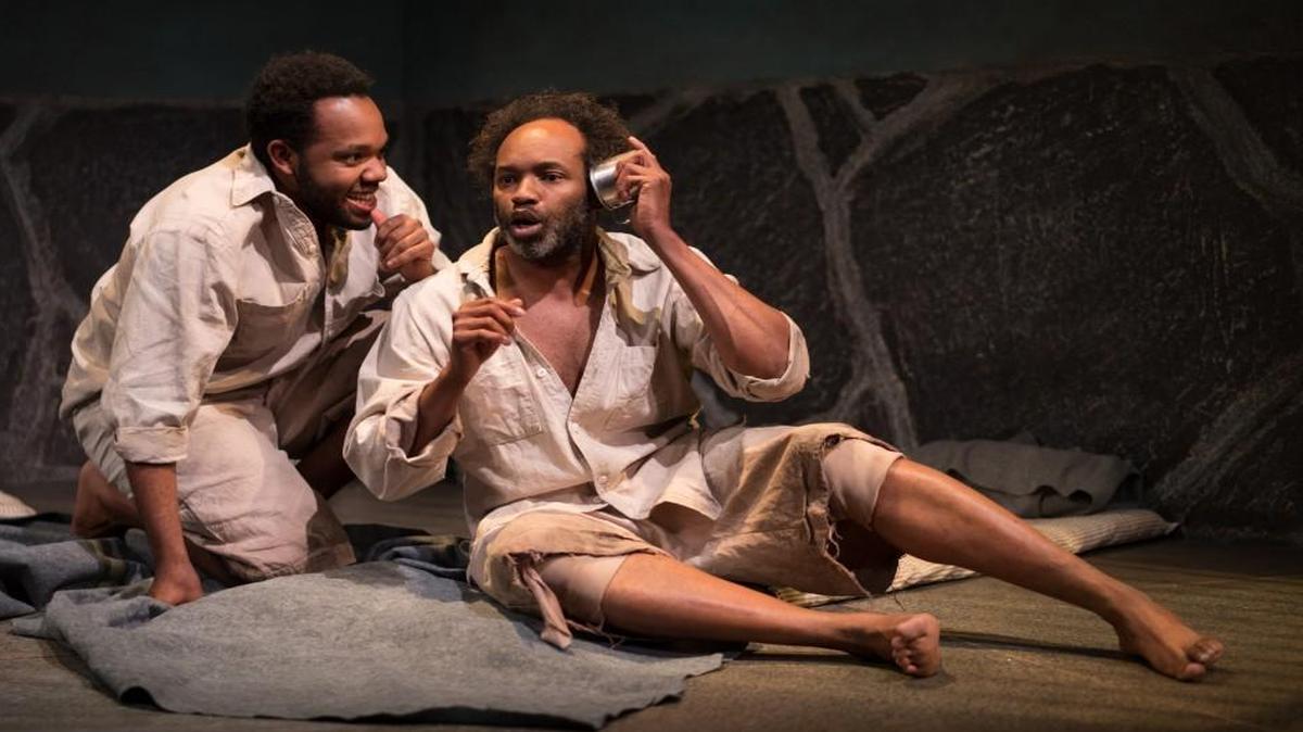 Teddy Trice (left) listens in as Damron Russel Armstrong has an imaginary phone conversation in “The Island.”