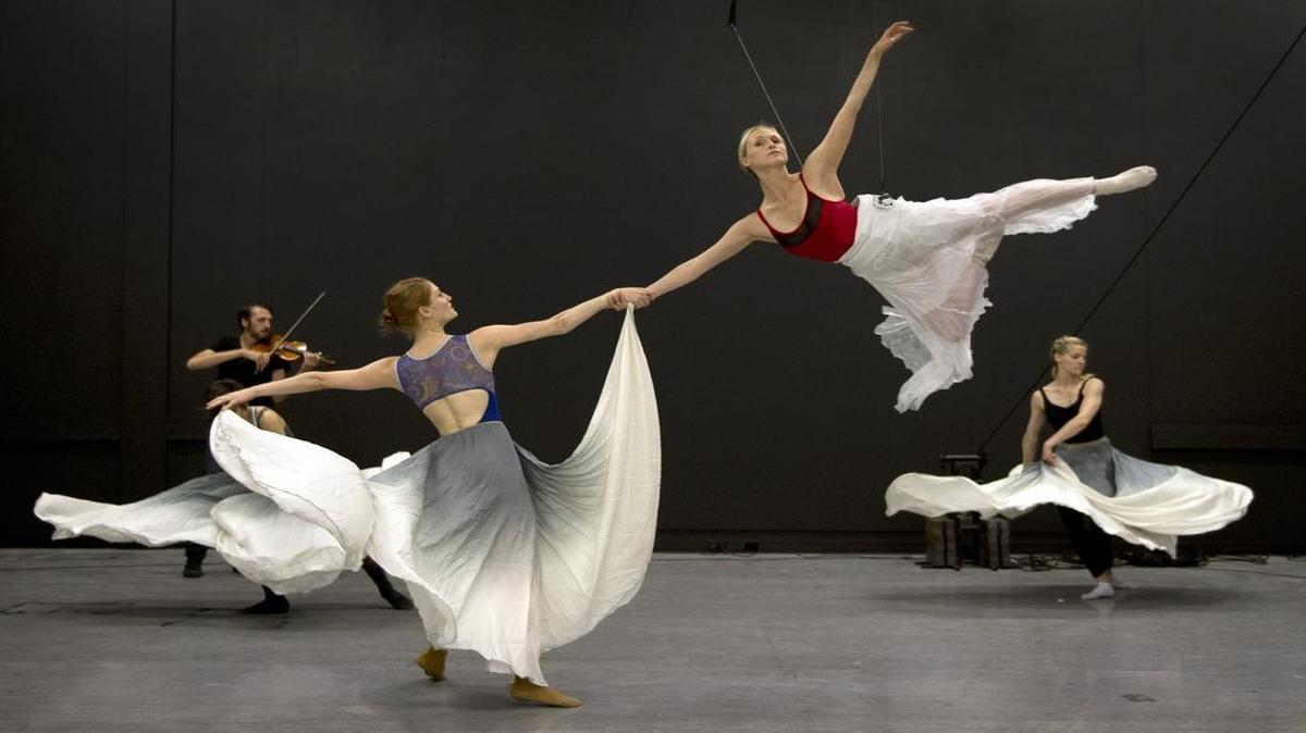 
Beau Campbell sailed through the air at a recent Quixotic rehearsal while being held by Laura Wallner. Shane Borth accompanied on violin while Christen Edwards (right) danced in the background. 
