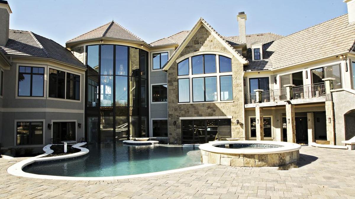 Three-story glass windows in the Home of Distinction built by Starr Homes overlook the pool complete with three infinity-edge waterfalls, built by Complete Pools.