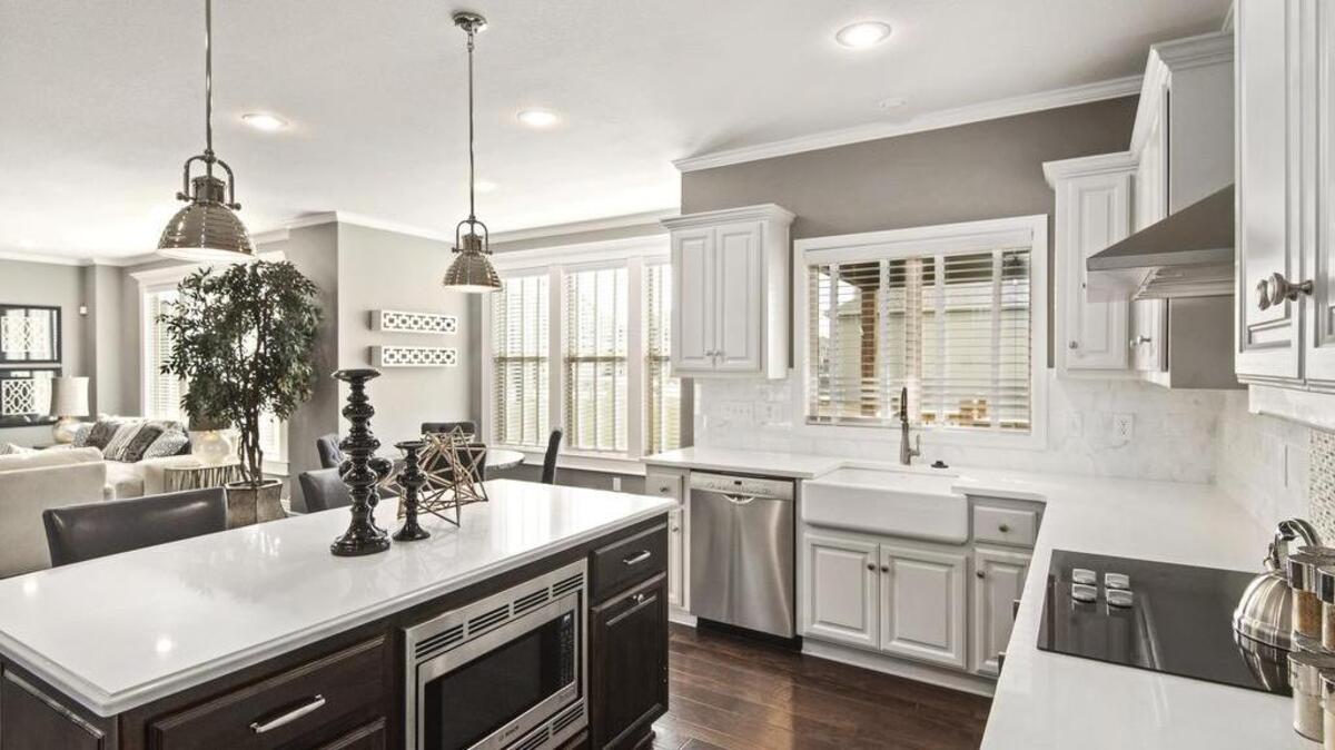 Custom enameled cabinetry and a large island with seating in the kitchen of the new Preston Ridge V model showcase ample storage and convenience for large families.