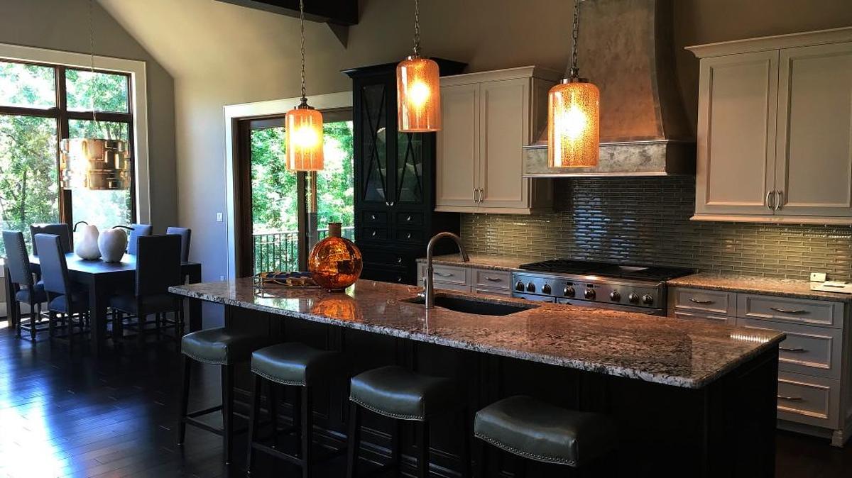 The fully equipped kitchen space includes ample cabinetry, a sizable kitchen island and top-of-the-line appliances. Yet the area is enhanced with a customized, handcrafted range hood that is a one-of-a-kind addition.