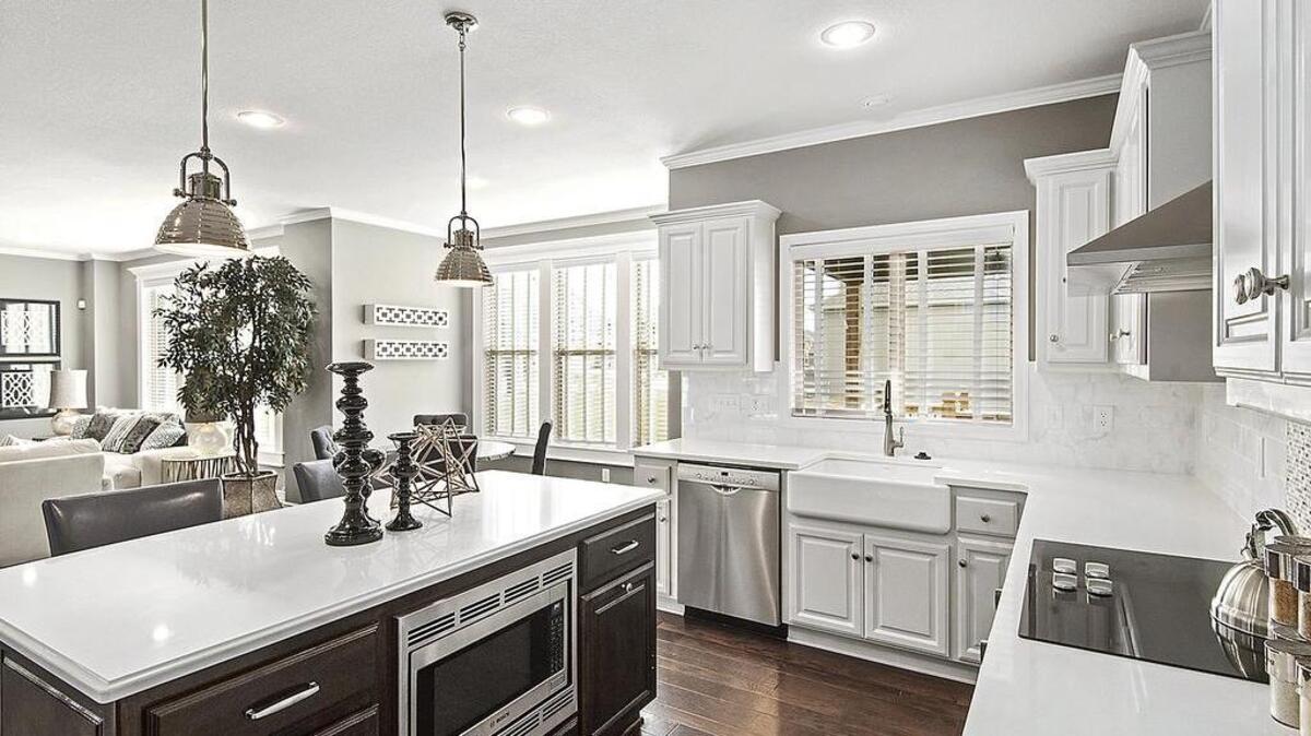 Custom enameled cabinetry and a large island with seating in the kitchen of the new Preston Ridge V model showcase ample storage and convenience for large families.