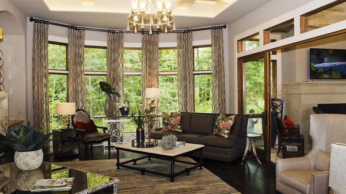 
The cosmopolitan-inspired great room of the Artisan Home Tour entry built by Willis Custom Homes has a bowed window bay that overlooks the treed back yard. The opening at right leads to a four-season room with yet another fireplace.
