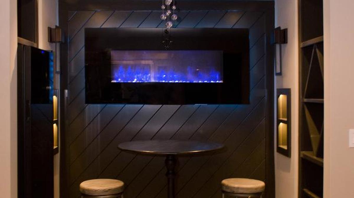 
The wine room on the lower-level of the home built by Willis Custom Homes is highlighted by an electric flame fireplace and is flanked by built-ins and a wine chiller. 
