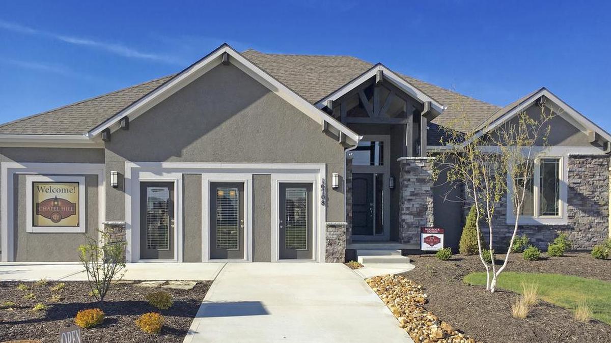 The Dillon reverse 1 ½-story model home by Rodrock Homes at 16708 Haskins showcases a walkout covered patio plus a covered deck with see-through fireplace, four bedrooms and a sleek, all-white kitchen featuring Bosch appliances and a separate wine refrigerator.