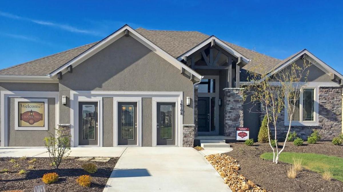 The Dillon reverse 1 ½-story model home by Rodrock Homes at 16708 Haskins showcases a walkout covered patio plus a covered deck with see-through fireplace, four bedrooms and a sleek, all-white kitchen featuring Bosch appliances and a separate wine refrigerator.