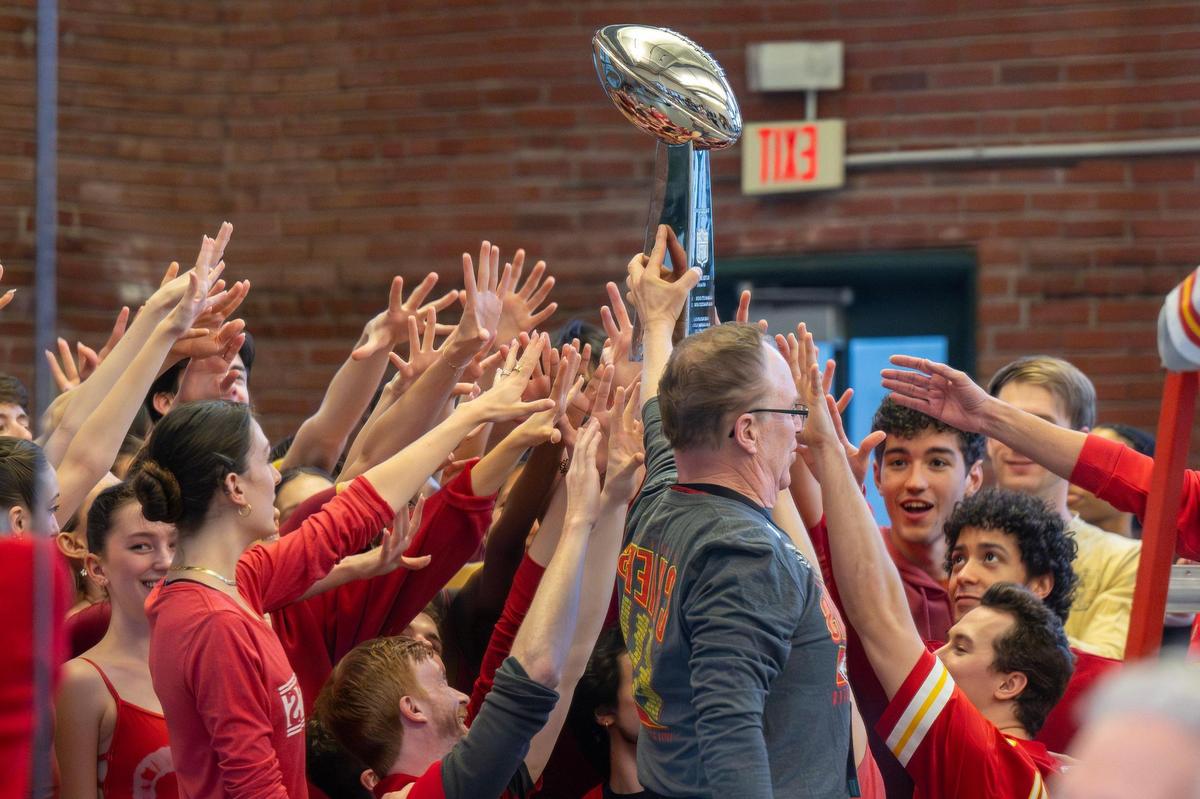 Dancers reach for the Lombardi Trophy loaned to them by former Kansas City Chiefs player John Lohmeyer for their production.