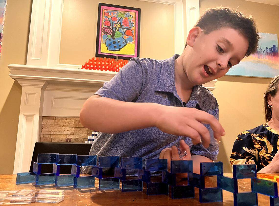 Noah Unell puts the finishing touches on one of his handmade menorahs built of dominoes.