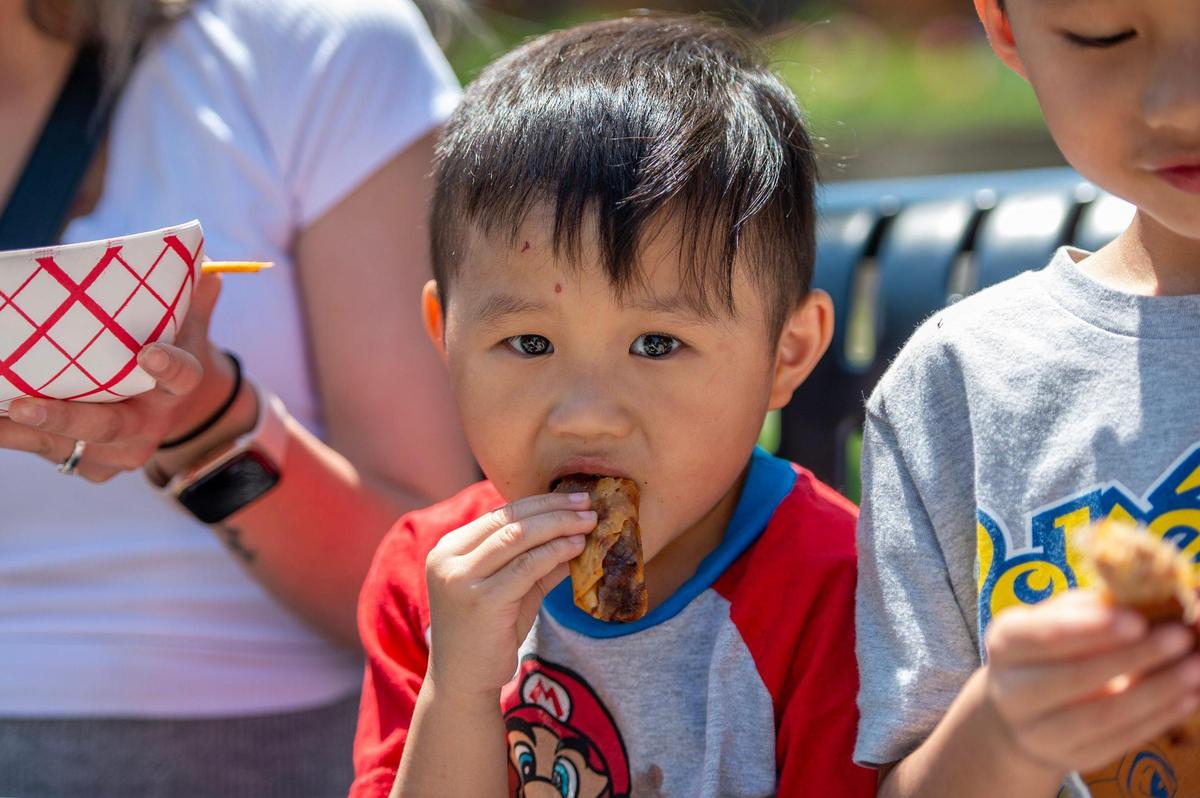Four-year-old Jaxxon Chamblerlin chows down on a egg roll from Laos House during the AAPIconic Festival on Saturday, May 20, 2023, in Kansas City.