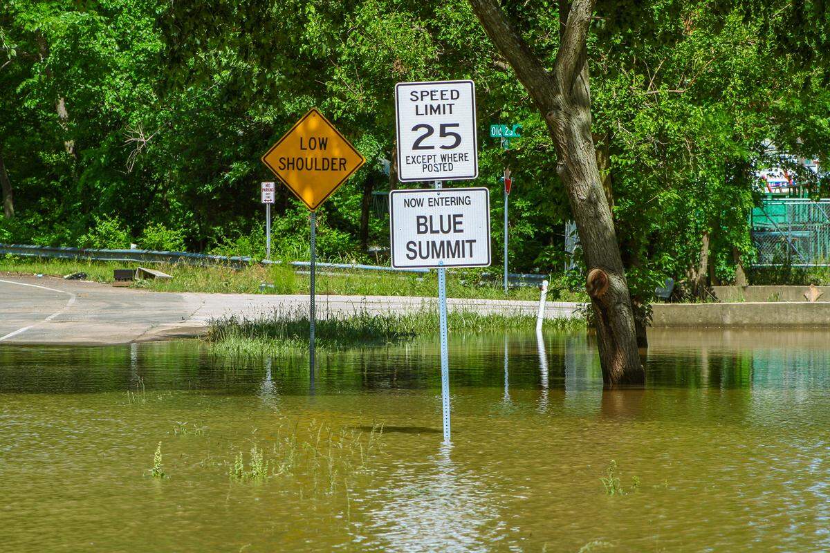 A sign marks where the Blue Summit neighborhood begins. It sits in flood water.