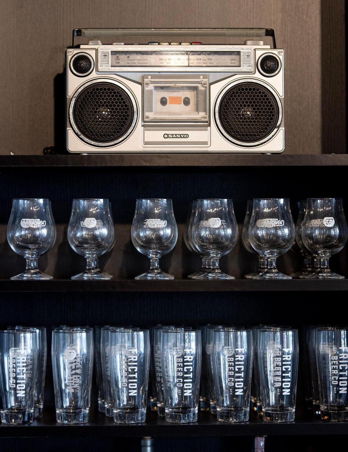 Beer glasses and a boombox line a shelf behind the bar at Friction Beer Co.