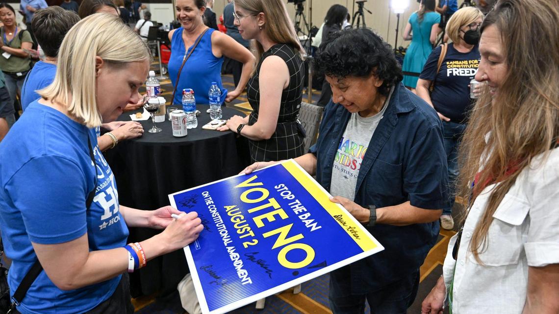 Kansas Democractic Representative Jo Ella Hoye of District 17, left, signed a Vote No sign held by Crystal, mother of Rep. Sharice Davids during the lKansans for Constitutional Freedom election watch party Tuesday, August 2, 2022, at the Overland Park Convention Center, 6000 College Blvd. The group was victorious at the polls as they backed a ‘No’ vote on the constitutional amendment, which if passed, removes the right to an abortion from the Kansas constitution.