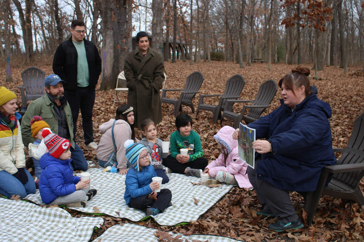 Katharine Garrison, education coordinator at the Overland Park Arboretum, reads “The Night Tree” to attendees of an arboretum program. Before the story, the group made edible ornaments for animals to eat that they later hung on trees.