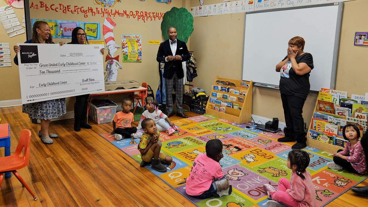 Avrell Stokes, co-founder and president of Be Great Together, surprises Robin Smith with $10,000. Smith is lead pre-K teacher at Grace United Community Ministries. Photo by Toriano Porter