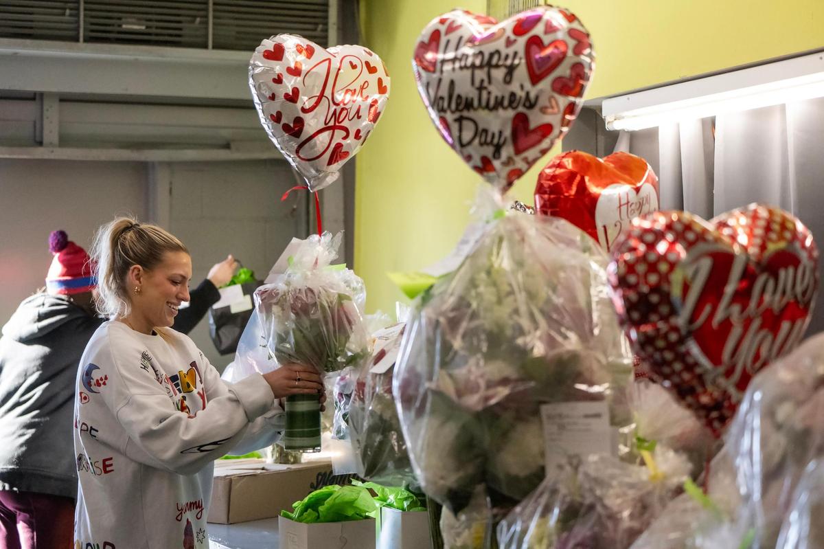 Ashlie Santini, left, a contract delivery driver for Toblers Flowers, and Grace Kost, contract help, prepare Valentine’s Day floral arrangements for delivery on Thursday, February 13, 2025, in Kansas City. The arrangements of fresh flowers need to be protected from the cold and are wrapped in plastic.