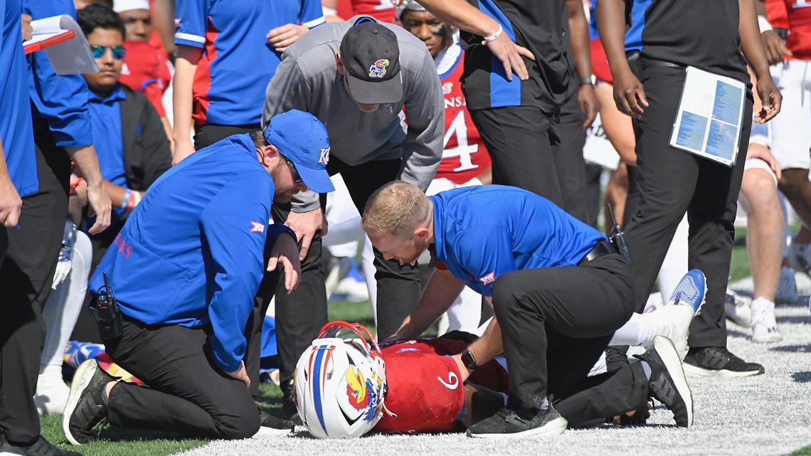 Kansas Jayhawks head coach, Lance Liepold, with black hat, checks on quarterback Jalon Daniels after he was injured late in the first half while playing TCU Saturday, October 8, 2022, at David Booth Memorial Stadium in Lawrence, Kansas.