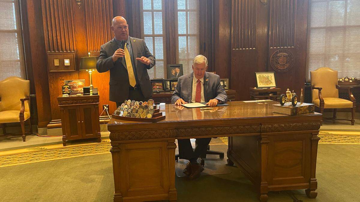 Rep. Chris Brown, a Kansas City Republican, (left) speaks as Missouri Gov. Mike Parson (right) signs a bill to block local governments from halting evictions. 