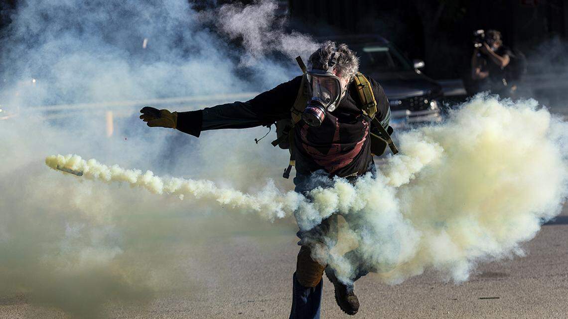 A protester throws a canister of teargas back at Immigration and Customs Enforcement officers in the western suburbs of Chicago Sept. 26.