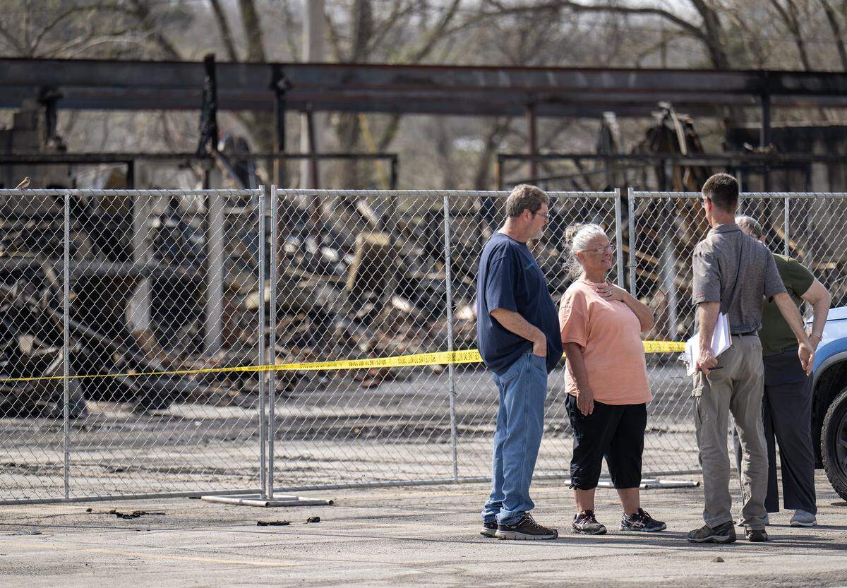 Nissa True, center, the owner of Smithville’s Pizza Shoppe, talks with visitors near the skeletal remains of a Smithville shopping center on Tuesday, March 31, 2026, less than 24 hours after a massive fire destroyed five businesses. The Monday afternoon blaze destroyed Smithville’s Pizza Shoppe, La Fuente Mexican Restaurant, H&R Block, Westlake Chinese Restaurant, and Lakeside Smoke.