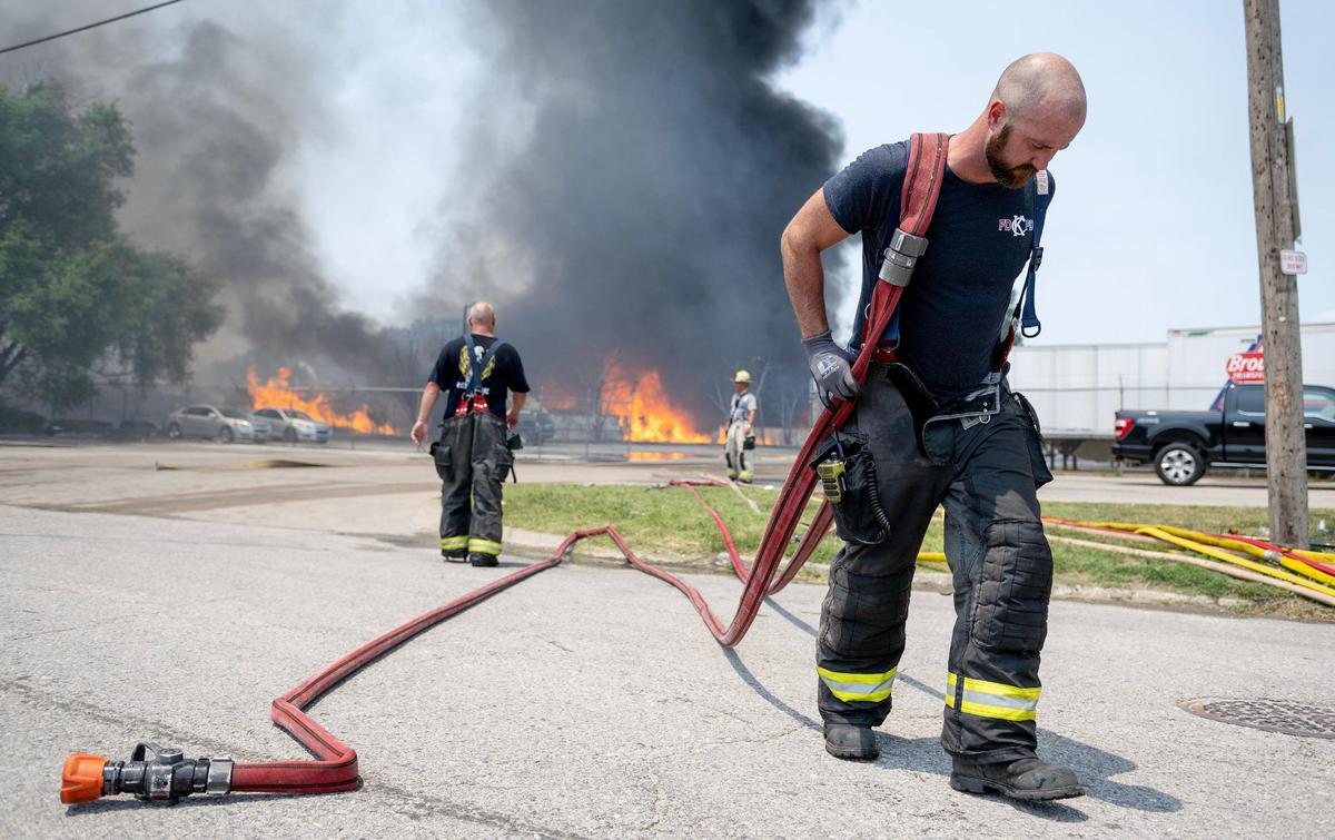 A firefighter drags a hose line while battling a blaze at Pioneer Pallet in the 3500 block of Nicholson Ave. on Thursday, June 15, 2023, in Kansas City.