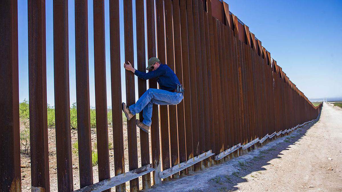 Cochise County, Arizona sheriff ranch patrol deputy Mike Magoffin demonstrates how easy it is to climb the border fence with Mexico.