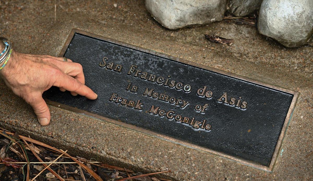 Jim Cosgrove points out Frank McGonigle’s name on the plaque in front of the St. Francis of Assisi statue at St. Peter’s Catholic Church on Meyer Boulevard.