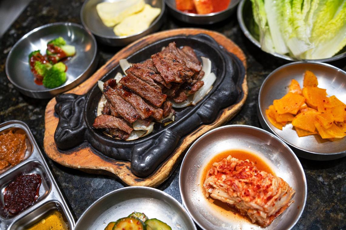Marinated short ribs are served with banchan, an assortment of side dishes including kimchi and pickled vegetables.