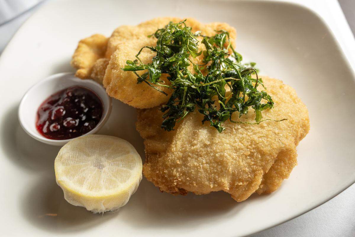 The Chicken Schnitzel, $24 with thin Buttonwood Farm chicken cutlets, breaded and pan fried, served with potato salad, cucumber salad, & lingonberry compote.