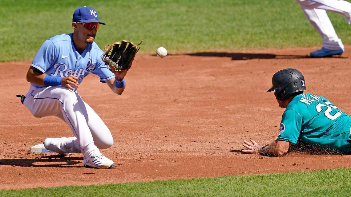 Seattle Mariners’ Dylan Moore (25) beats the tag by Kansas City Royals shortstop Nicky Lopez to steal second during the second inning of a baseball game Sunday, Sept. 19, 2021, in Kansas City, Mo. (AP Photo/Charlie Riedel)