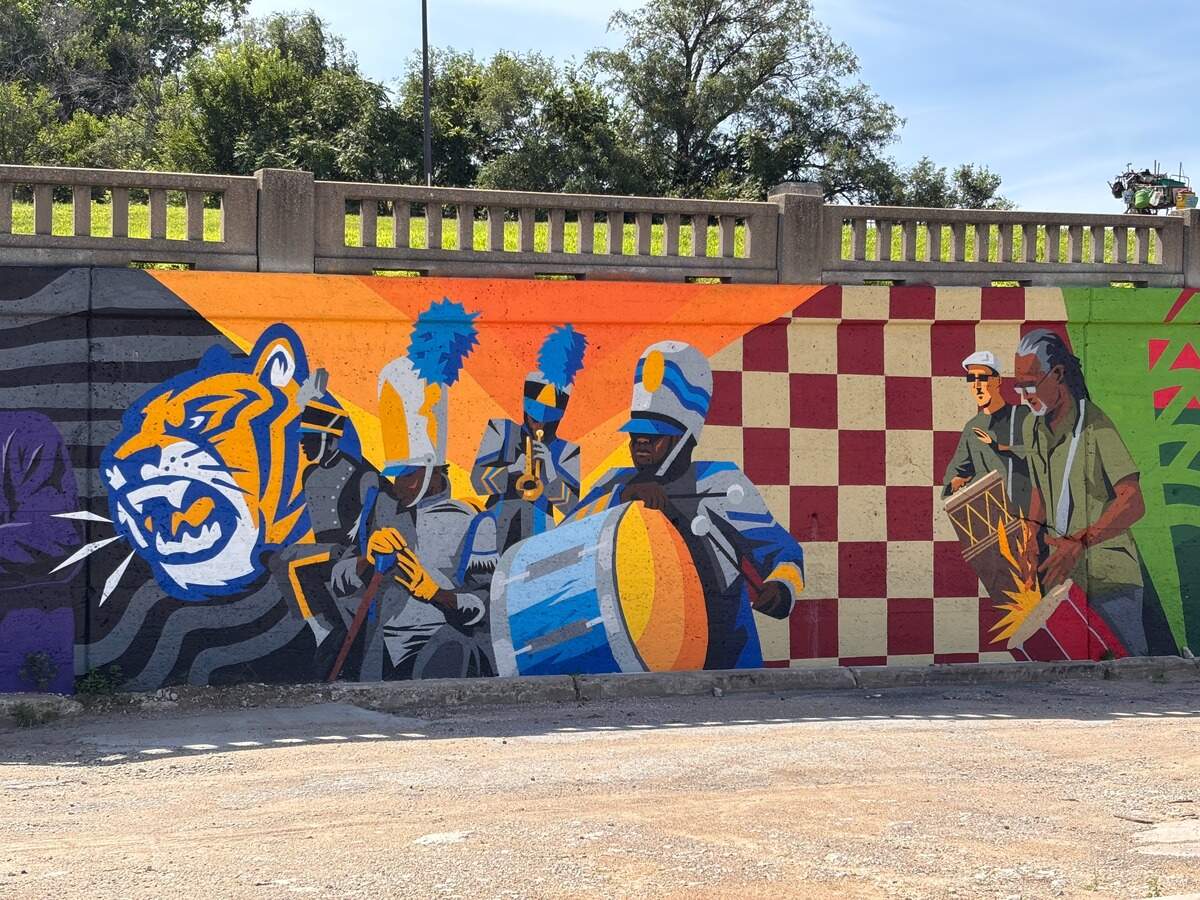 The artwork features a tribute to African drummer Bird Fleming with by depictions of marching band culture, referencing Lincoln High School band.