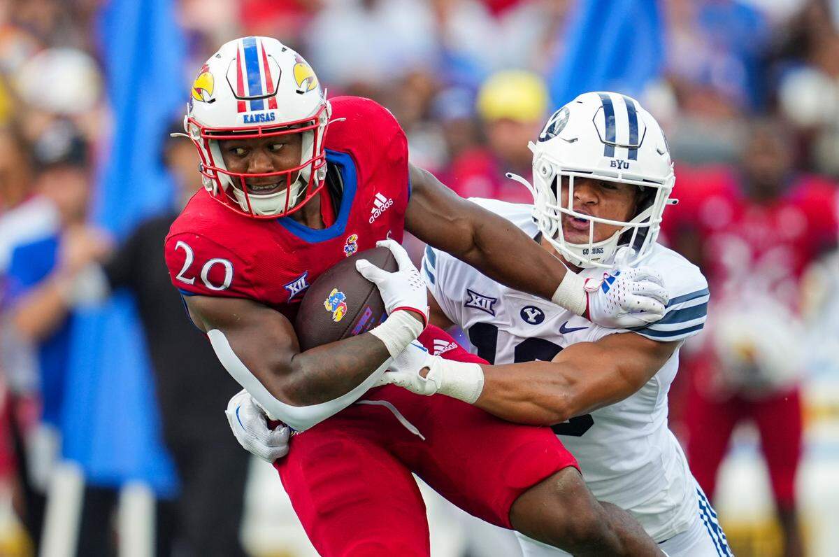 Kansas Jayhawks running back Daniel Hishaw Jr. (20) is tackled by BYU Cougars linebacker Ace Kaufusi (18) during the second half at David Booth Kansas Memorial Stadium on Sept. 23, 2023.