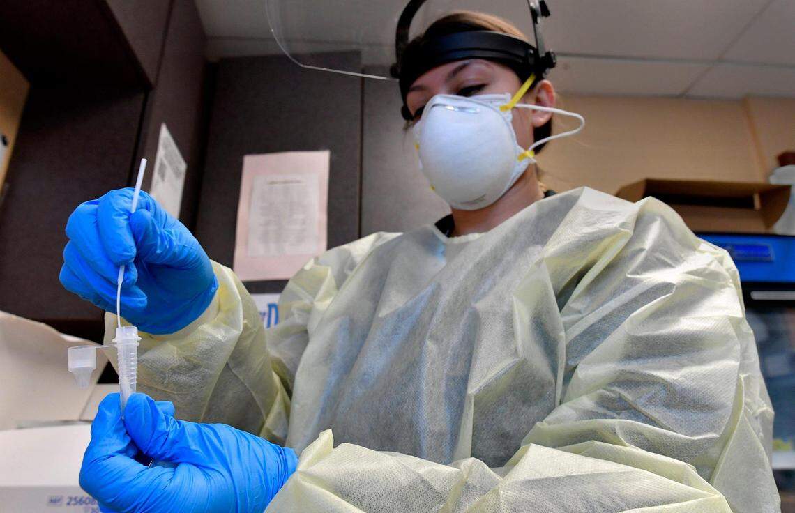 Medical assistant Breana Slusser takes a nasal swab from a drive-thru patient and tests it for COVID-19 Tuesday at the Family Health Care Clinic in Kansas City, Kansas. Doctors are recommending such tests before the holidays.