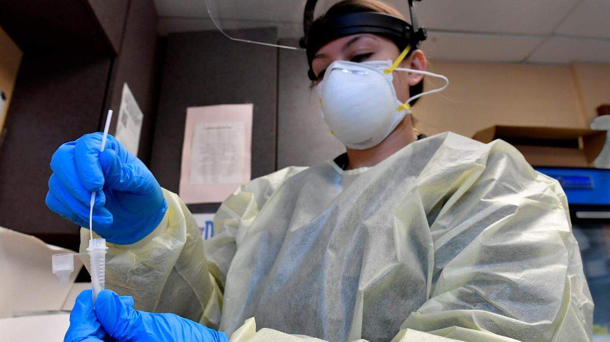 Medical assistant Breana Slusser takes a nasal swab from a drive-thru patient and tests it for COVID-19 Tuesday at the Family Health Care Clinic in Kansas City, Kansas. Doctors are recommending such tests before the holidays.