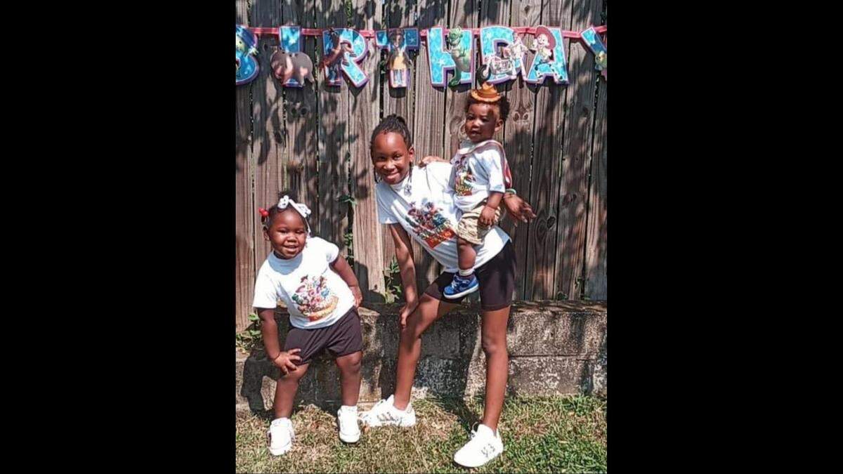 Lauren smiles for a picture with her younger sibling, London, 2, on her hip, and Leeyah,5, mimicking her pose.