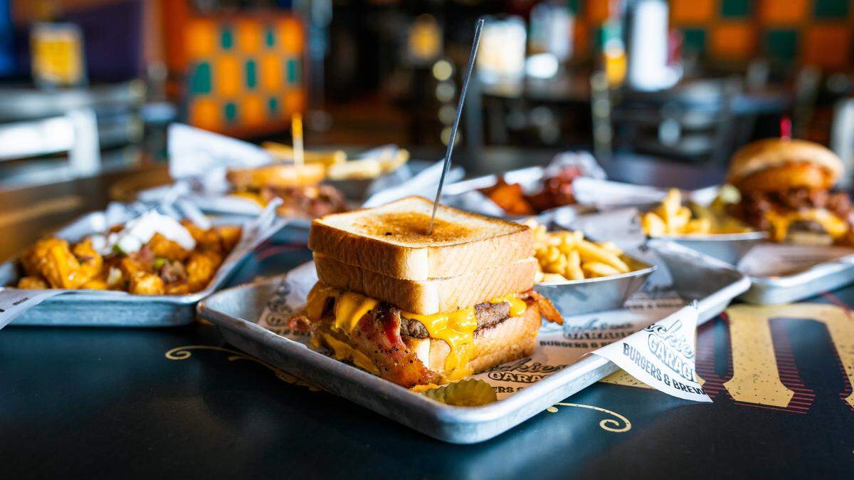 Sickies Twin Cam burger with peppered bacon and nacho cheese between two grilled cheese sandwiches for buns.