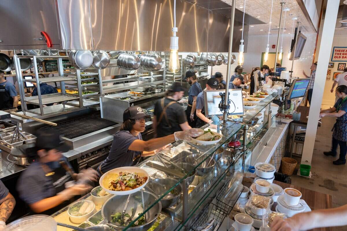 Chefs, line cooks, and trainees swiftly navigate the front counter station at the new Flower Child restaurant on Friday, Aug. 7, 2026.