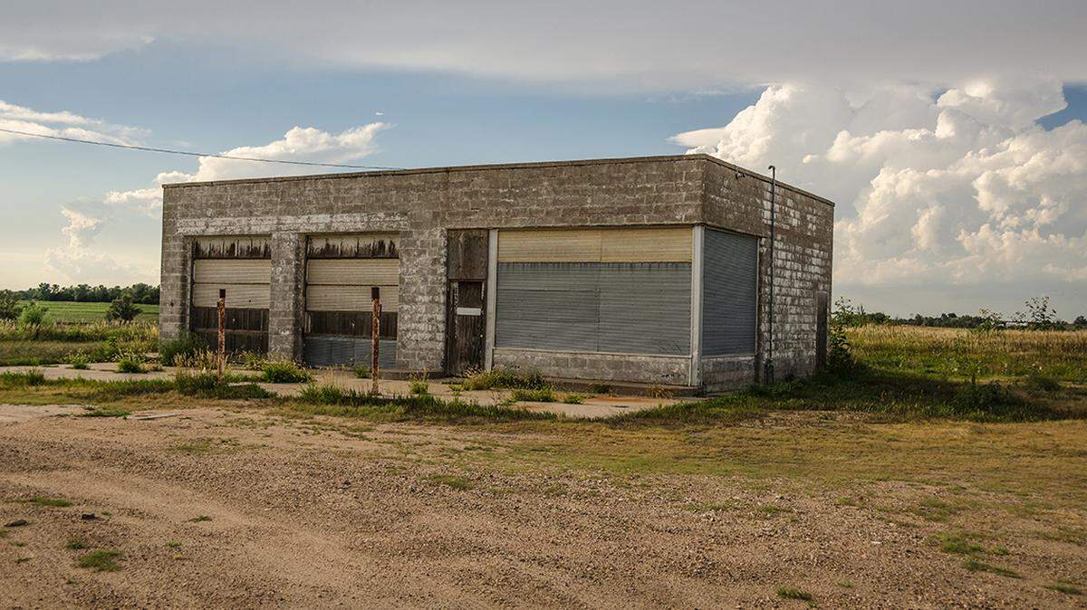 Vacant and abandoned service station with peeling paint and rusted posts in rural USA