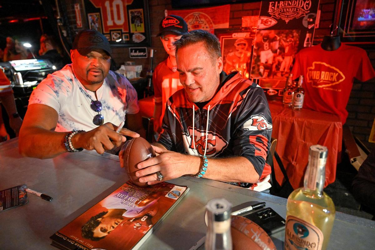 Former Kansas City Chiefs greats Neil Smith, a defensive end, and Nick Lowery, a kicker worked together to steady a football to be autographed Wednesday, Feb. 8, 2023 at Pub Rock Live, a bar in Scottsdale, Arizona, with a large following of Chiefs fans.