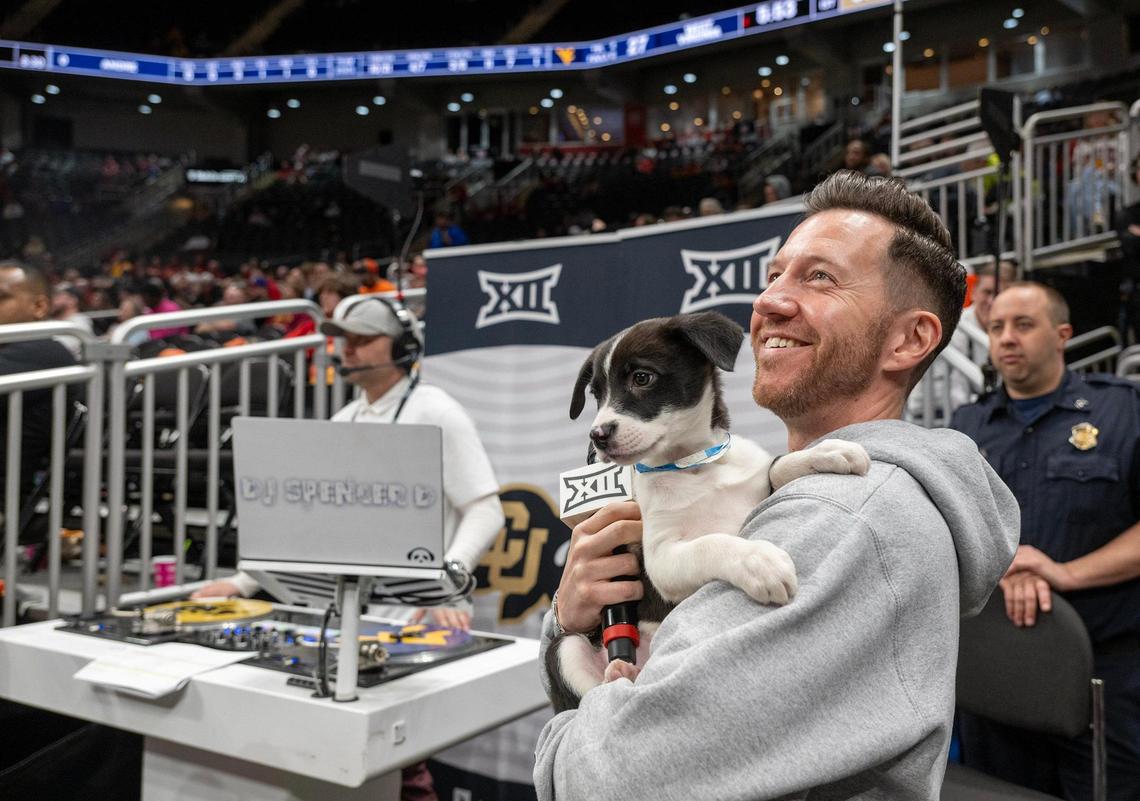 Tyler Banks, master of ceremony for the Men’s Big 12 Basketball Tournament, held a shelter puppy court side Wednesday, March 13, 2025, at the T-Mobile Center in Kansas City. Best Friends Animal Society of Kanab, Utah, teamed up with the Big 12 Conference The Humane Society of Greater Kansas City to sponsor the event and spur adoptions. All the puppies on hand Wednesday were adopted.